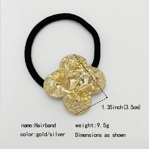 Detail view of a black elastic hairband with a 3.5cm gold clover-shaped metal charm