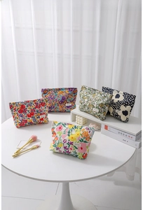 Detailed arrangement of colorful floral makeup bags on a white table with soft lighting