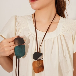 Detail of irregular resin pendant necklace in amber and dark green with long cord