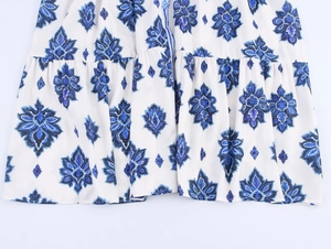 Detalle de estampado paisley azul y dobladillo con volantes en vestido largo blanco