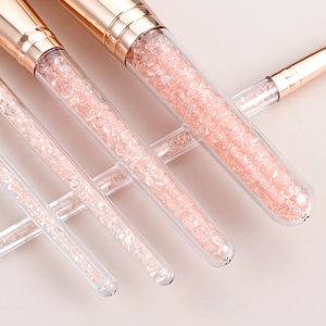 Detail of clear makeup brushes filled with pink crystals and rose gold ferrules