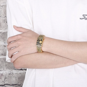 Detailed view of men's gold stainless steel skull chain bracelet on a male wrist