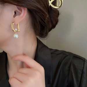 Eleganti orecchini a lettera D in oro con perle bianche indossati da modella