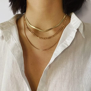 Detailed close-up of triple-layered gold necklaces with snake and Figaro chain styles