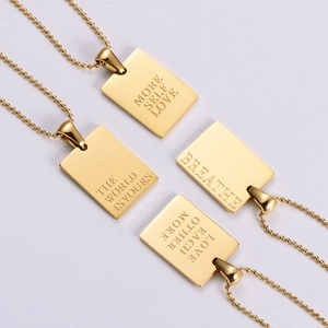 Close-up of square gold necklaces with More Self Love engraved inscriptions on metal tags