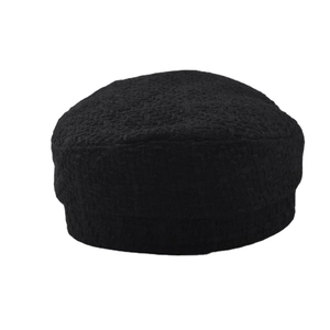 Close-up of black boucle textured fabric and gold chain detail on the military style hat