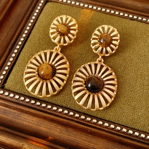 Detail of vintage gold tiger eye earrings on green velvet display with wood frame
