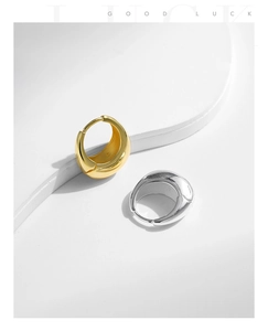 Detailed view of polished thick hoop earrings in gold and silver finish on white steps