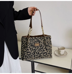 Detail of leopard print tote bag with chain strap and leather patch on canvas texture