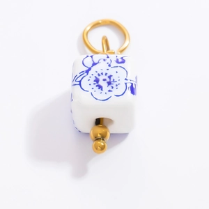 Détail macro du pendentif en perle céramique fleur bleue avec anneau en métal doré
