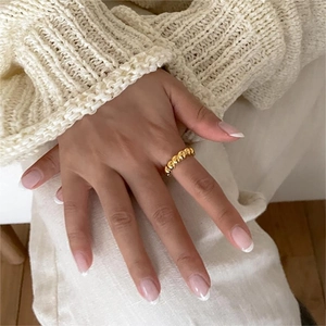 Detail of a gold rope textured 925 sterling silver ring worn with a cream knit sweater