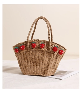 Close-up of handmade straw tote with cute knitted red strawberries and green leaves