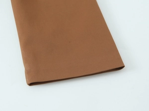Detailansicht der dunkelbeige Twill-Stoffstruktur und Nähte am Ärmelabschluss