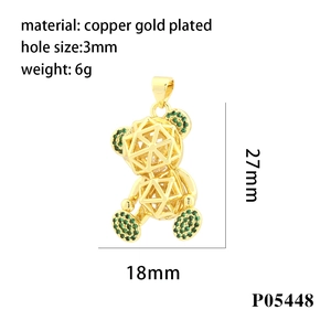Detail view of a 27mm x 18mm micro-pave bear pendant in gold-plated copper with green accents