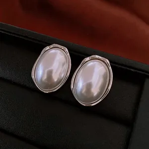 French retro oval pearl stud earrings with elegant silver metal frame on a leather box