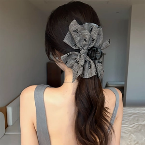Macro shot of large grey fabric bow hair claw clip showing textured material on long hair