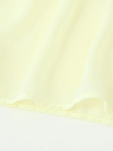 Macro detail of pleated light yellow chiffon fabric with high-quality hem stitching