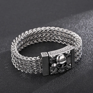 Macro detail of men's stainless steel skull bracelet with vintage silver woven chain links
