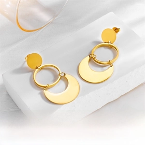 Detailed close-up of golden geometric crescent earrings on a minimalist stone base