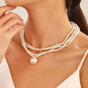 Close-up of layered white pearl necklace with large pendant on a model neck