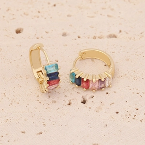 Detailed macro shot of gold hoop earrings set with colorful rectangular zircons on stone