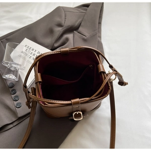 Detail view of brown pebbled leather bucket bag with drawstring and red interior pocket