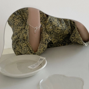 Close-up of minimalist silver chain bracelet with T-bar clasp on wrist over mirror
