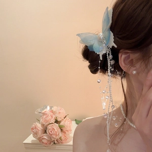 Detail of blue tulle butterfly hair clip with elegant long pearl tassels on a model