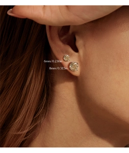 Gros plan de boucles d'oreilles dorées en 6mm et 8mm portées sur l'oreille