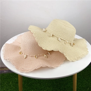 Detail of woven straw hats with decorative seashells and elegant wavy brim edges