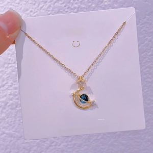 Dettaglio della collana con luna dorata e pianeta Saturno blu con cristalli e catena