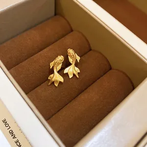 Boucles d'oreilles poisson doré plaqué or avec finition mate dans une boîte à bijoux