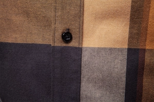 Gros plan sur le tissu en coton à carreaux marron et gris avec détail de bouton noir