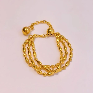Detailed macro view of triple-layered golden beaded adjustable bracelet with polished finish