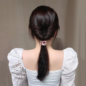 Pink floral hair scrunchie styling a low ponytail on a model with white lace blouse