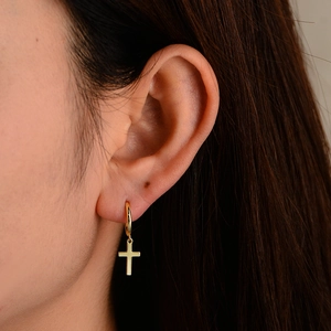 Gros plan détaillé d'une personne portant la boucle d'oreille croix en argent s925 doré