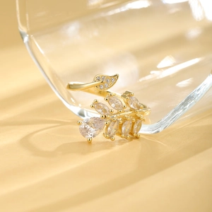 Golden leaf open ring with micro-p鑲ed zircons on a glass background