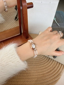 Detail of vintage oval gold watch with double-strand pearl bracelet and white dial