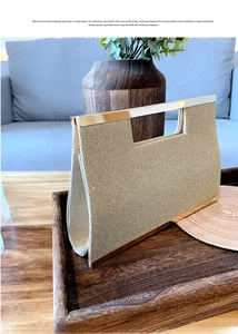Close-up of golden evening clutch with metal woven texture and rectangular top handle
