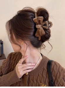 Close-up of a brown velvet bow hair claw clip worn on a woman's hair in a retro style
