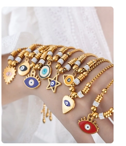 Stacked evil eye charm bracelets with colorful enamel and gold finish on a model wrist