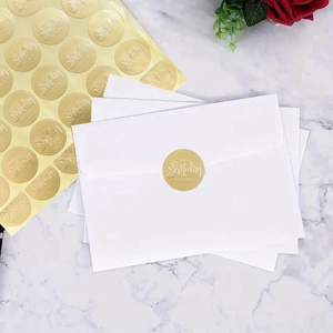 Detail of round gold foil Happy Birthday stickers on white envelopes and marble background