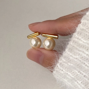 Detail von Vintage-Perlenohrringen mit Goldstab, gehalten vor weißem Pullover