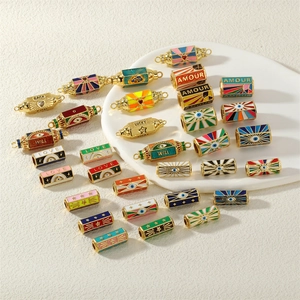 Golden enamel evil eye beads and charms for DIY jewelry making displayed on a white plate