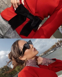 Detail of red wool coat with large black velvet bow and stylish pleated waist design