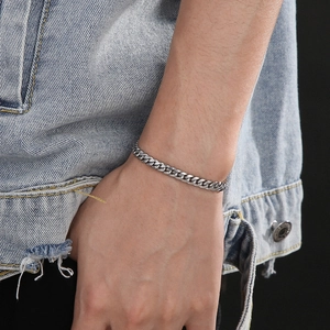 Close-up of a silver stainless steel Cuban link bracelet worn by a male model on his wrist