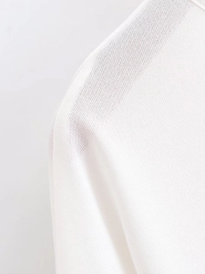 Close-up of white knit fabric texture and shoulder seam detail on batwing sleeve dress