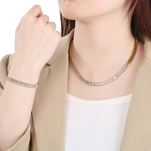 Detailed view of gold-plated tennis and Cuban chain jewelry set on a model in a beige suit