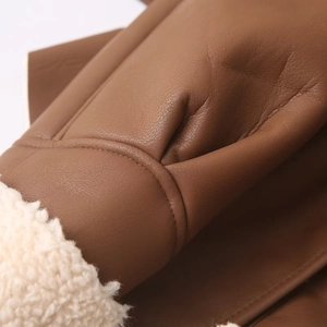 Gros plan sur les coutures du cuir marron et la doublure en fausse fourrure blanche douce