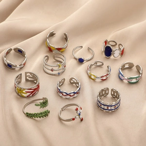 Flat lay of colorful enamel drip heart rings with hollow chain designs and open bands